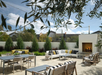 Relaxing outdoor patio with daybeds, tables with chairs, and fireplace.