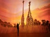 A person stands at sunset, pointing towards two giraffes in a grassy landscape.
