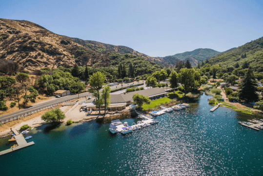 Aerial view looking down on the The Lodge at Blue Lakes  and their marina full of boats in deep blue water with mountain in the background.