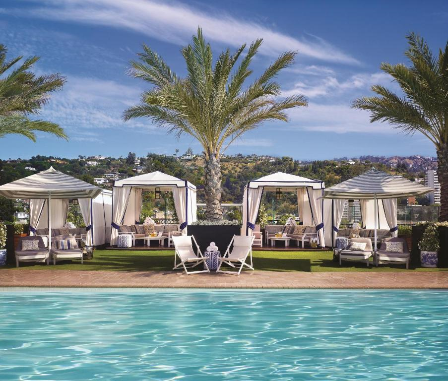 Poolside view with palm trees and cabanas under a clear blue sky.