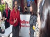 A man in a red shirt wearing a head set speaking to a woman in a gray suit with a woman in a black dress behind them on the Hollywood Behind-the-Scenes Walking Tour.
