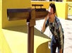 A man in a plaid shirt and glasses putting his eye and hand up to look through a a brown telescope at The Fantastic Race.