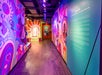 A brightly lit hallway features colorful, psychedelic wall art and informational text about the musical "Hair" on the right wall.