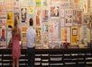 Two people stand in front of a wall filled with colorful, vintage-style posters in a store.