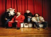 The Oak Ridge Boys pose with a red curtain in the background