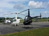 A black helicopter and a white helicopter parked on a landing pad as part of the Helicopter Sightseeing Tour.
