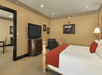 One king bed, bedside lamp, TV, and seating area in a guest room.