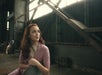 Emma Pittman as Cherry Valance wearing a lavender cardigan sitting in a warehouse with large windows behind her.