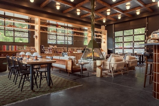 The lounge area in the lobby of the The Ozarker Lodge with a fire pit, couches, a table and chairs, and a coffee and wine bar.