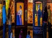 People observing interactive historical displays depicting life-sized figures in period costumes set against a brick wall.