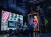 Kristin Chenoweth and ensemble with Wall Street imagery projected behind them.