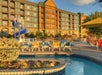 Outdoor pool area with lounge chairs and a blue water slide, set against a multi-story hotel building in the background.