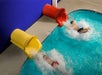 Two people splash into a pool from yellow and red water slides, one wearing red shorts and the other black shorts.
