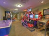 Arcade room with an air hockey table, racing game machines, and a pinball machine in a brightly lit hallway.