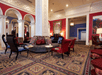 A lounge area with ornate carpet, red and white walls, and red and black furniture in the lobby of the The Royal Sonesta Portland Downtown.