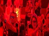 People wearing 3D glasses and holding devices engage in an interactive theater experience, seated in futuristic chairs under red lighting.