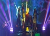 A group of singers performing on a dark stage at the Magic of Terry Evanswood at The Grand Majestic.