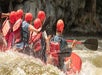 A group of people in red helmets splashing into the water at Smoky Mountain Rafting on the Upper Pigeon River.
