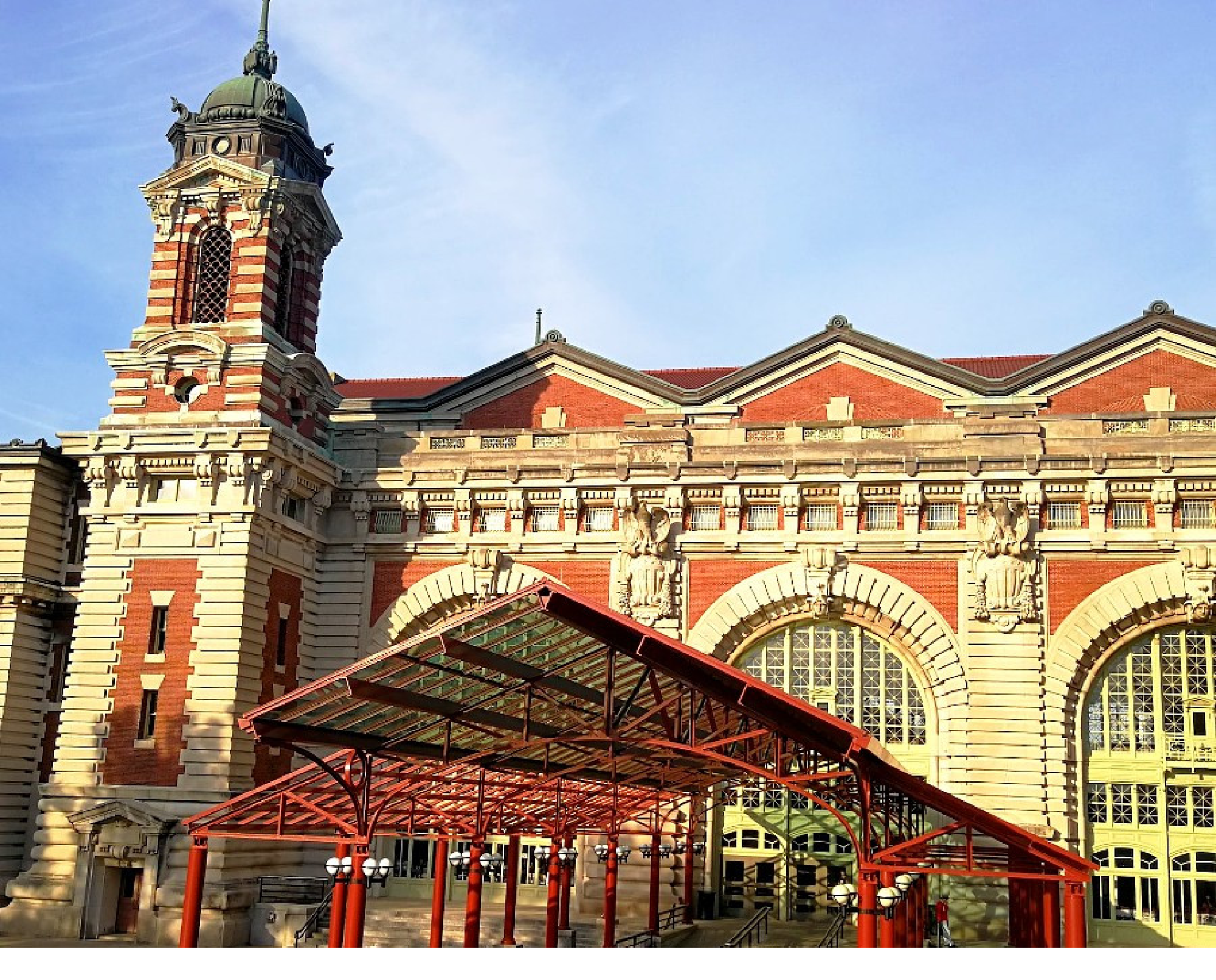 Ellis Island Immigration Museum with arched windows and a clock tower, under a blue sky.