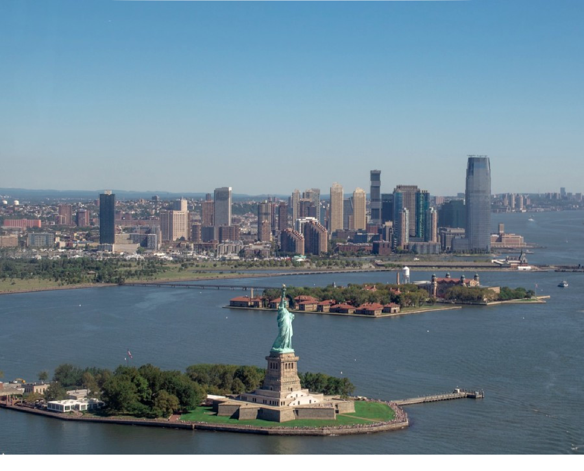 Aerial view of the Statue of Liberty on Liberty Island with the Manhattan skyline in the background.