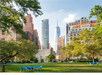 A park with blue chairs on grass, surrounded by trees and tall city buildings in the background under a clear sky.