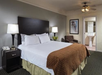 One king bed and an arm chair inside a guest room.