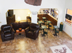 Hotel lobby with tiled floor, leather sofas, coffee tables, and a TV on one side; small dining area with tables and chairs adjacent to a beverage and snack station.