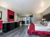 One king bed, bedside lamps, seating area, wet bar with coffee maker, desk, and TV in a guest room.