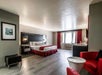 Two queen beds, bedside lamps, seating area, desk, and TV in a guest room.