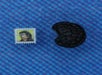 A small postage stamp and a bitten Oreo cookie are placed side by side on a blue textured surface.
