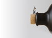 A miniature figurine of a man appears to push a cork into the top of a large bottle against a plain white background.