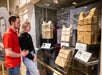 A man and woman observe vintage life jackets displayed in a museum exhibit, with informational placards visible below each artifact.