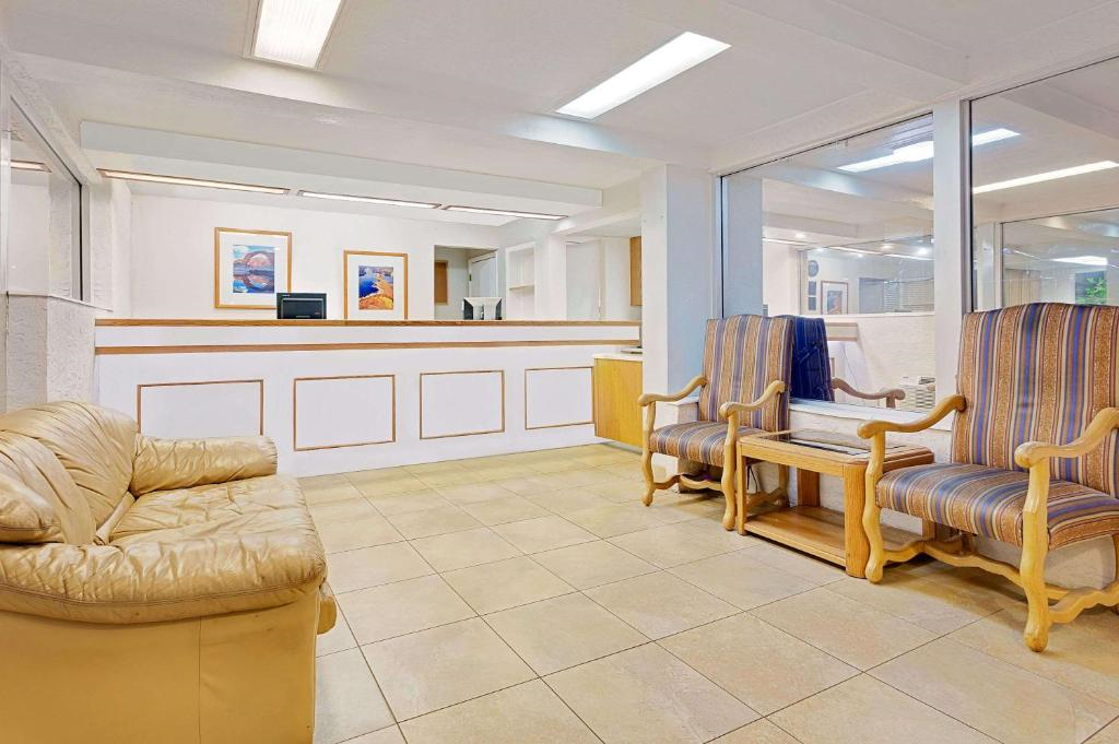 A waiting room with a sofa, two striped armchairs, and a small coffee table. A reception desk is visible in the background under fluorescent lighting.