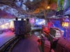 A dimly lit, colorful cave-themed amusement ride features a mine cart on tracks, surrounded by antique décor and glowing lanterns.