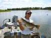 A woman smiles while holding her large bass catch