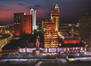 Aerial view of an illuminated casino and hotel complex at dusk, with multicolored lights and a crowd gathered outside.