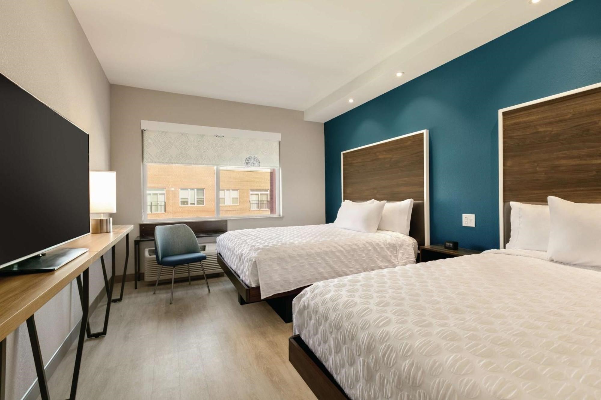 Two-queen guest room at Tru by Hilton Charlotte Ayrsley with modern beds, television, and window