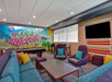 Colorful lounge area with modern seating, a pool table, and a wall mural reading "Welcome to Fort Walton Beach.