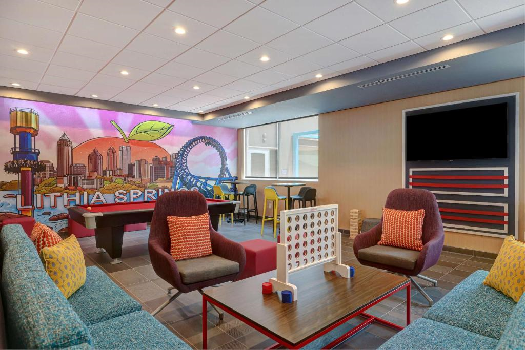 Modern lounge with colorful mural, pool table, Connect Four, and seating. Wall-mounted TV and windows with natural light.
