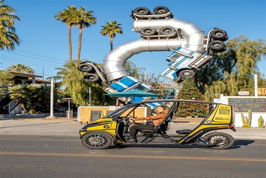 A woman driving a doorless GoCar past a train sculpture on a sunny day in Las Vegas, Nevada.