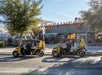 Two yellow GoCars with tourists in them parked on the side of the road on a sunny day in Las Vegas.