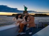 A couple poses on a boat at sunset with the Statue of Liberty visible in the background.