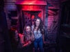Three scared guests let out a scream as a scareactor peeps out from a door behind them.