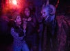 Three guests screaming as they encounter a scareactor dressed as a demon in "The Darkest Deal" haunted house.