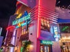 The exterior of a Margaritaville restaurant at night, illuminated by colorful neon signs and surrounded by tropical-themed decor.