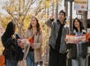 Four people walk outdoors holding maps and brochures, with trees and a "Black History Month" sign visible in the background.