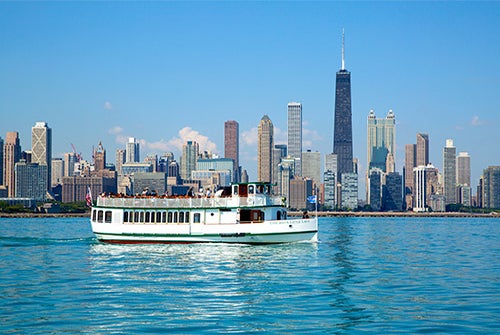 The cruise ship with Chicago's Cityscape behind it on the Urban Adventure Cruise in Chicago, Illinois, USA.