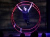 A man in all black performing acrobatics on a red metal wheel at V - The Ultimate Variety Show in Las Vegas, NV.