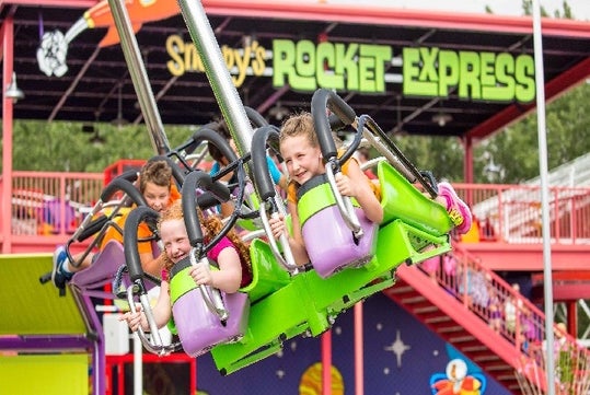 Young girls riding Snoopy's Rocket Express and smiling on a sunny day at Valleyfair in Bloomington, Minnesota.