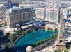 Aerial view of the Las Vegas Strip featuring the Bellagio Hotel, Caesars Palace, and a replica of the Eiffel Tower beside a large fountain.